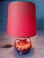 Lamp illuminated showing red shade and glazed base