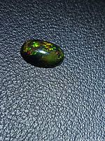 Top view of oval cabochon Ethiopian black opal showing play of color
