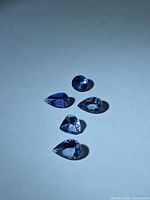 Five faceted tanzanite stones arranged on a neutral background