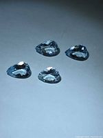 Four pear-cut aquamarine gemstones arranged on white surface