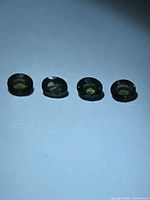 Four oval green sapphires side-by-side on white background