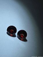 Both round red garnets showing color and cut