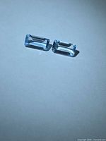 Two rectangular light blue gemstones on white background