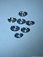 Eight small oval tanzanite gems on white background