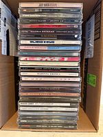 Stack of CD jewel cases showing spines with artist and album titles