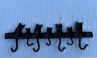 Front view of entire cast iron rack with seven cats and six hooks