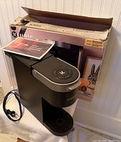 Keurig K-Slim coffee maker with manual on drip tray beside original box