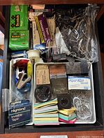 Drawer view showing boxed tapes, staples, binder clips, paper clips, notes, tape dispenser, stapler remover