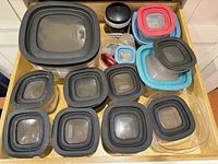 Drawer view of all clear plastic Rubbermaid containers with assorted colored lids