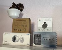 Four boxed items: Chromecast, EZVIZ C3N camera, digital wildlife camera, brown boxed device