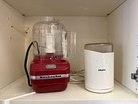 KitchenAid food processor and Krups grinder side by side on shelf