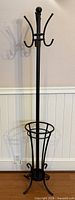 Full view of black metal coat rack showing hooks, umbrella ring, legs