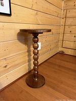 Full view of wooden spindle pedestal table showing round top, turned spindle column and round base