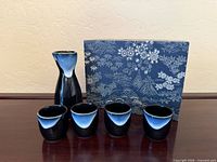 Front view of stoneware sake set with carafe, four cups and box