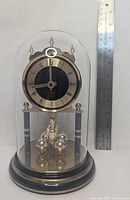 Front view of mantel clock showing dial, glass dome, base and size ruler