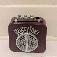 Front view showing burgundy casing, silver grille and logo