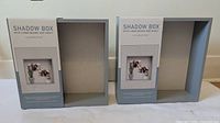 Front of both shadow boxes showing gray frames and linen backs