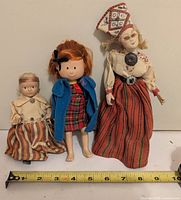 Front view of all three dolls with measuring tape