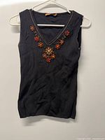 Front view of black sleeveless knit top hanging on hanger