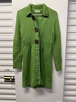 Full view of green knit cardigan coat hanging