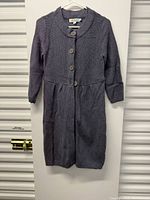 Front view of charcoal grey knit jacket on hanger showing three-button closure and shawl collar