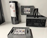 Three Storage Essentials baskets (one open, two collapsed) and sealed black cylinder