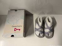 Sandals beside Skechers box, top view