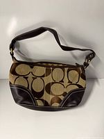 Front view of Coach signature jacquard shoulder bag showing fabric pattern and leather trim