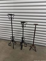 Three iron candle holders standing side by side showing overall design and size differences