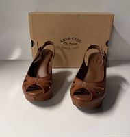 Front view of both sandals with box behind