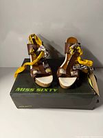 Front view of pair of Miss Sixty brown leather wedge sandals on original box