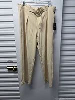 Front view of beige DKNY trousers hanging