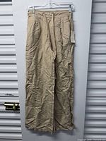 Full view of beige trousers hanging