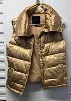 Full view of gold Talbots puffer vest hanging