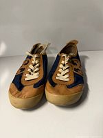 Front view showing lace-up closure, navy fabric and tan leather toe caps