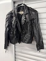 Full view of black leather fringe jacket hanging