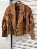 front view of tan suede fringe jacket on hanger