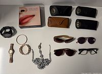 All items laid out: makeup set, eyewear with cases, watches, bracelets, necklace