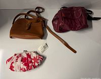 Overview of three bags: tan crossbody, burgundy shoulder, floral clutch