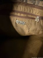 Interior of Fendi bag showing silver-tone Fendi SAS made in Italy label and brown fabric lining