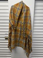 Full view of tan plaid fringed scarf hanging, showing pattern and fringe