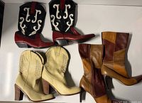 All three pairs of women’s boots laid out: red/black western, cream western, patchwork tall