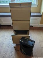 Filing cabinet front view with one drawer open and shredder in foreground