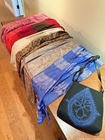 Full lot overview on bench showing eight scarves and shoulder bag