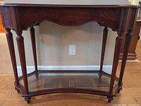 Front view of Bombay mahogany console table showing turned legs and lower glass shelf