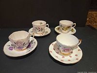 Group shot of four teacup and saucer sets showing patterns and gold trim