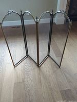 Full view of four-panel brass fireplace screen standing unfolded