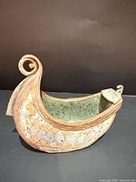Left side view of ceramic viking boat showing textured exterior and green glazed interior