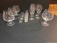 All 15 clear glasses arranged: 4 snifters, 5 wine, 6 shot