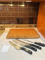 Cutting board with three knives and honing rod displayed on countertop